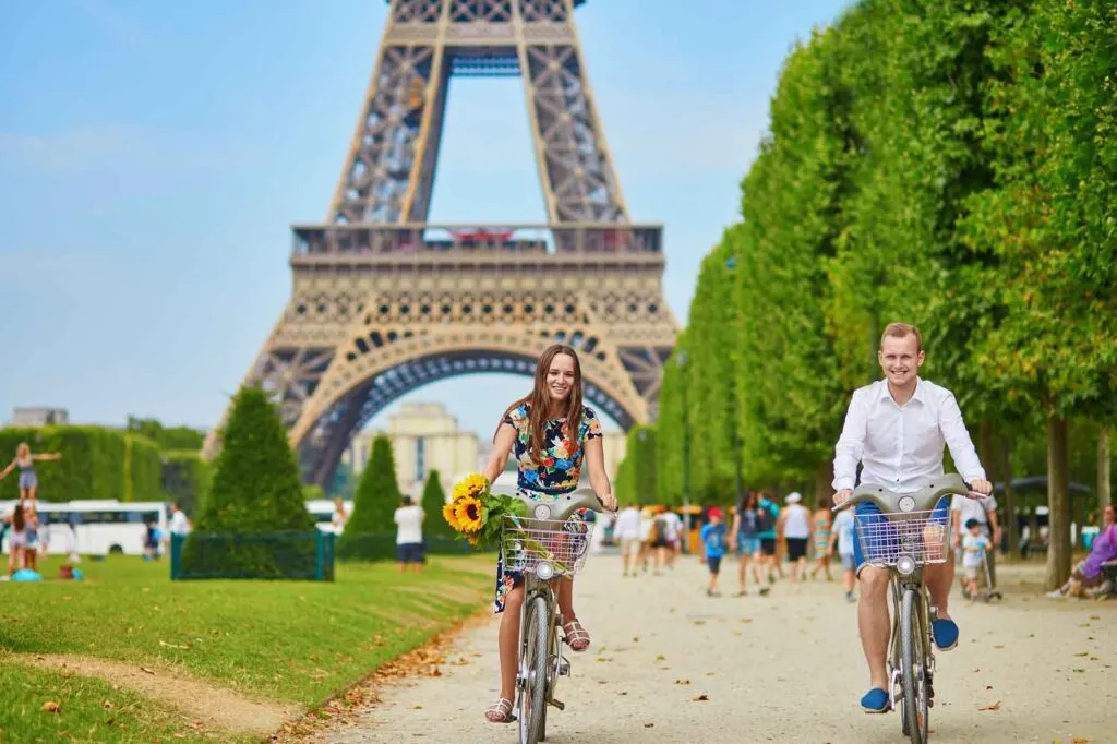 Young romantic couple of tourists using bicycles near the Eiffel tower in Paris