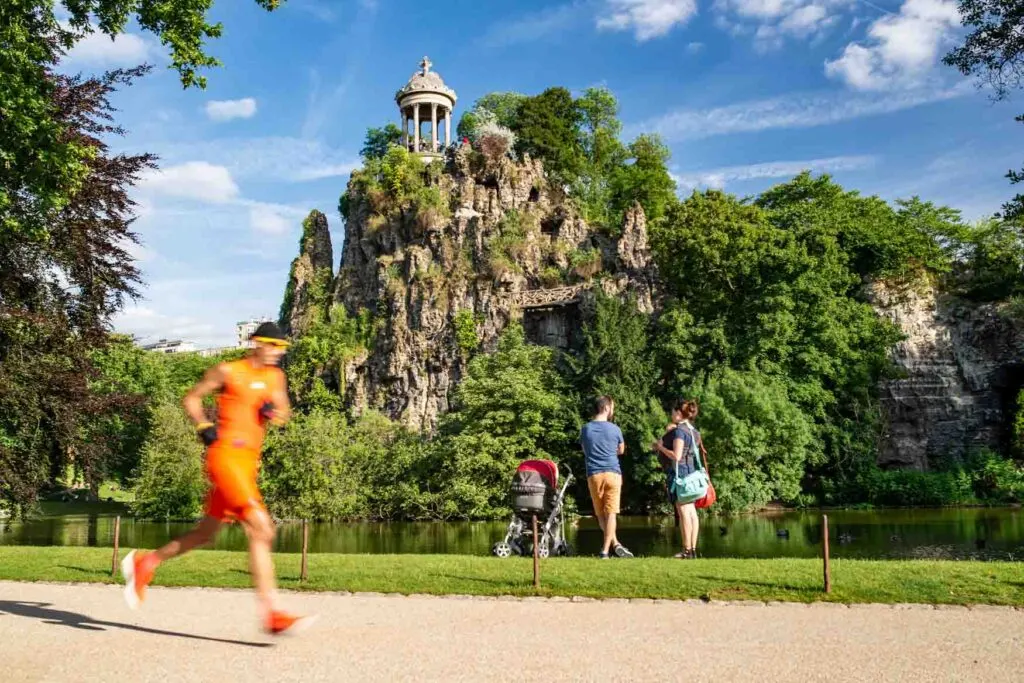 A family with one child and on runner dressed in orange in Buttes Chaumont Park