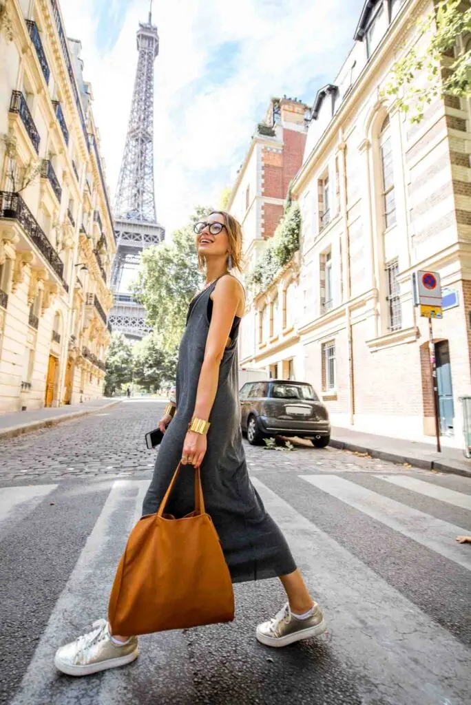 Young stylish woman walking the street with Eiffel Tower on the background in Paris