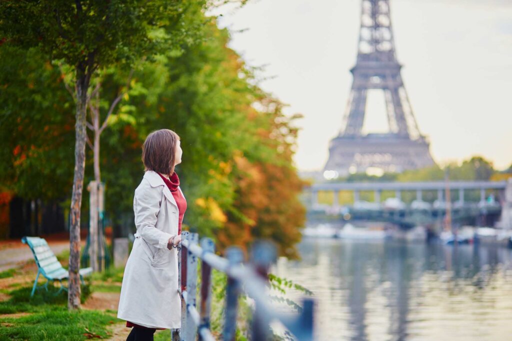 Beautiful young woman in Paris looking at the Eiffel Tower and the Seine on a bright fall day