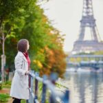 Beautiful young woman in Paris looking at the Eiffel Tower and the Seine on a bright fall day