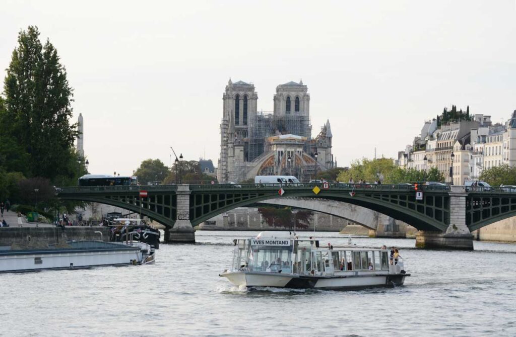 Boat passes under Pont Sully bridge with Notre Dame in the background