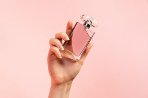 A woman's hand elegantly holds a glass of a French perfume brand