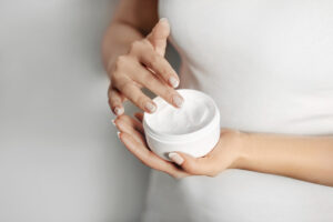 Closeup of female hands applying French skin care cream
