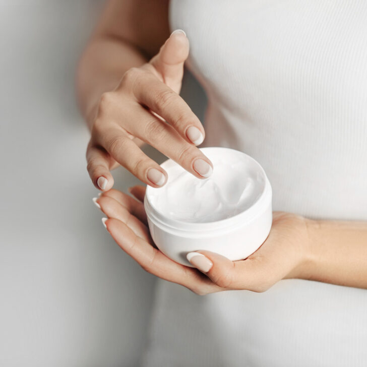 Closeup of female hands applying French skin care cream